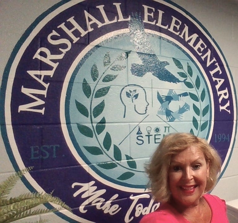 Mrs. Jensen smiling in front of Marshall mural